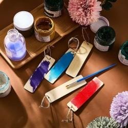 Selbst bemalte Lesezeichen aus Holz mit Farbtöpfen und Pinseln.