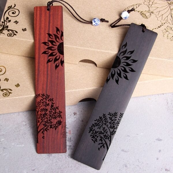 Zwei handgefertigte Lesezeichen aus Holz im chinesischen Stil mit lasergravierten Sonnen- und Baummotiven.