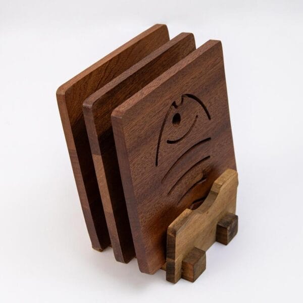 Set aus vier quadratischen Untersetzern aus Ebenholz mit Fischmotiv, in einem Holzständer.