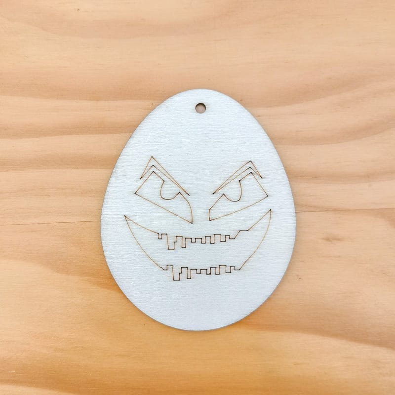 Lasergeschnittenes Halloween-Ei aus Holz mit gruseligem Gesicht. DIY-Dekoration.