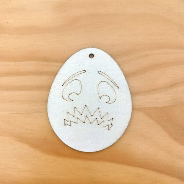 Hölzernes Osterei mit einem verängstigten Gesicht, perfekt für selbstgemachte Halloween-Dekorationen.