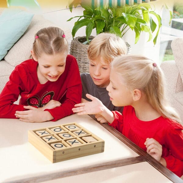 Drei Kinder spielen ein Tic-Tac-Toe-Spiel aus Holz.