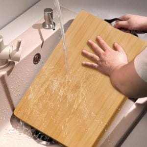 Großes Bambus-Schneidebrett wird in einer Küchenspüle abgespült.