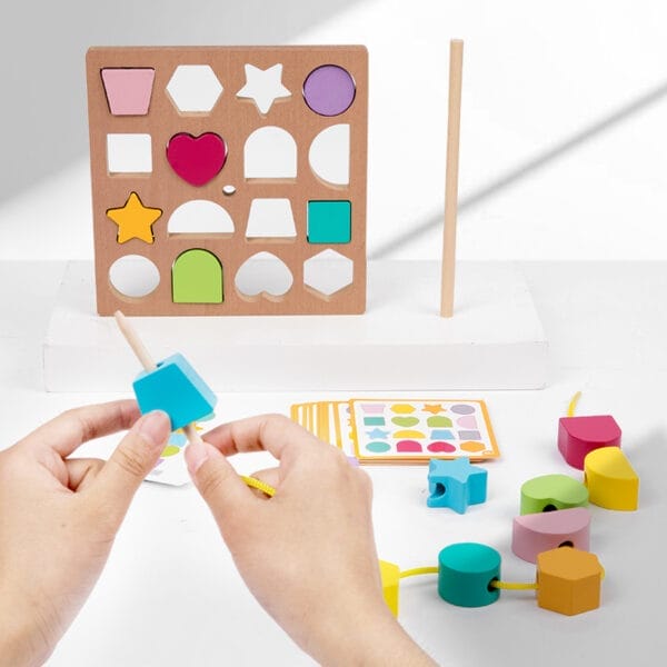 Kind spielt mit buntem Holzformsortierer und Perlenschnüren. Spielzeug für die frühkindliche Bildung.