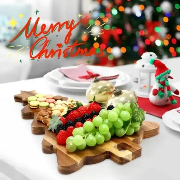 Serviertablett aus Holz in Form eines Weihnachtsbaums mit Obst und Snacks, Aufschrift „Frohe Weihnachten“.