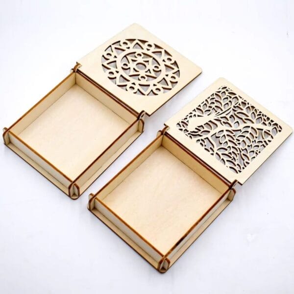 Zwei lasergravierte Holzkisten, eine mit Mandala- und eine mit Baummotiv, öffnen sich und geben den Blick auf ihr Inneres frei. DIY-Geschenkboxen.