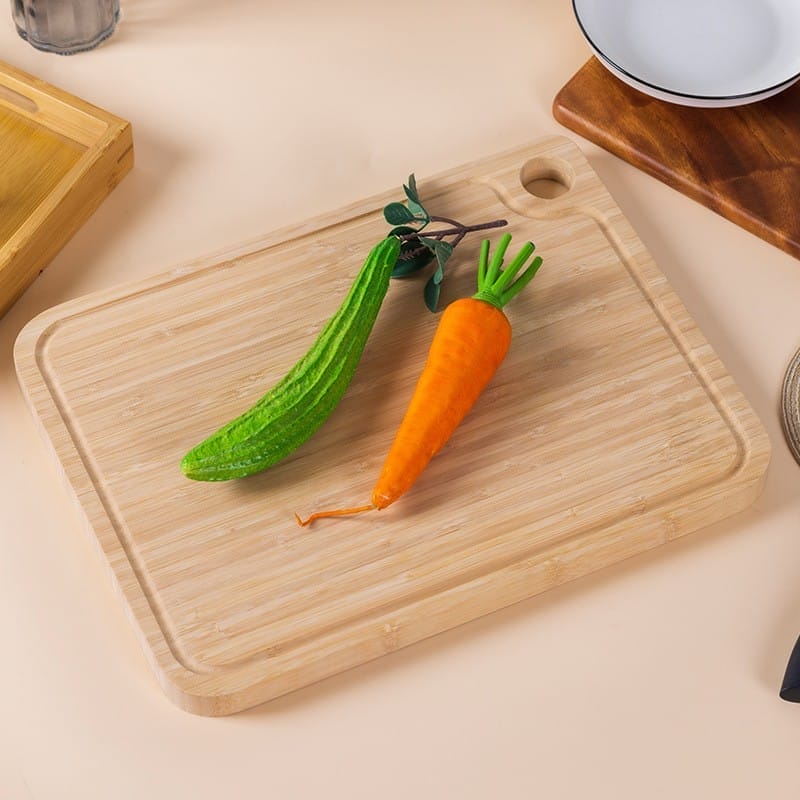Rechteckiges Bambus-Schneidebrett mit Griffloch, mit Luffa und Karotte.