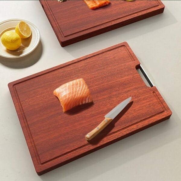 Zwei Schneidebretter aus Kirschholz, eines mit Lachs und einem Messer. Antibakterielles Küchenschneidebrett.