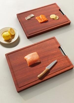 Zwei Schneidebretter aus Kirschholz mit Lachsfilets und Zitronen. Antibakteriell und ideal für die Küche.