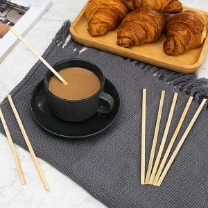 Bambus-Kaffeerührer und eine Tasse Kaffee auf einer grauen Oberfläche. Großhandels-Holzrührer.