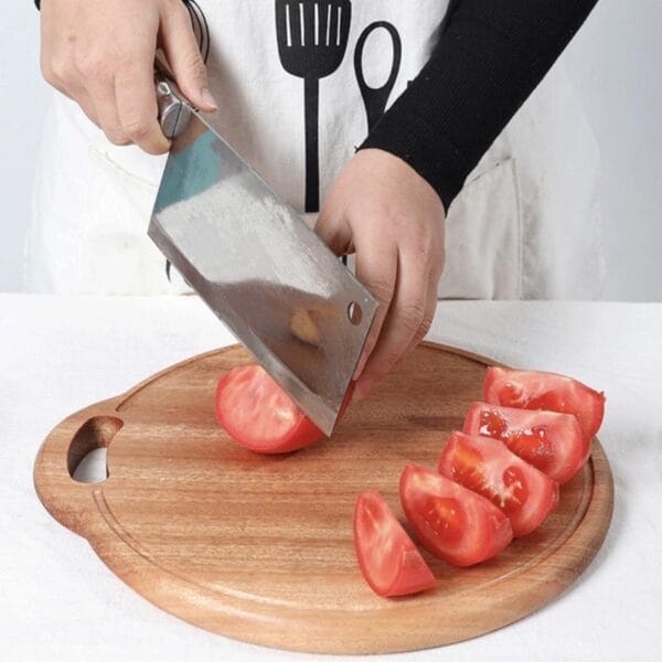 Person schneidet Tomaten auf einem hölzernen Schneidebrett. Holz-Schneidebrett im Einsatz.