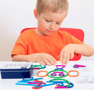 Kind spielt mit bunten Puzzlestäben in einer Metalldose. Großhandel Puzzle.