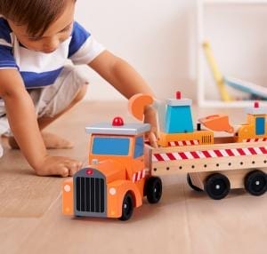 Kind spielt mit einem Baufahrzeug und einem Bagger aus Holz. Realistische Spielzeugfahrzeuge aus Holz.