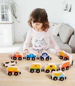 Kind spielt mit einem magnetischen 11-teiligen Holzeisenbahnspielzeug mit Fahrzeugen und Zahlen.