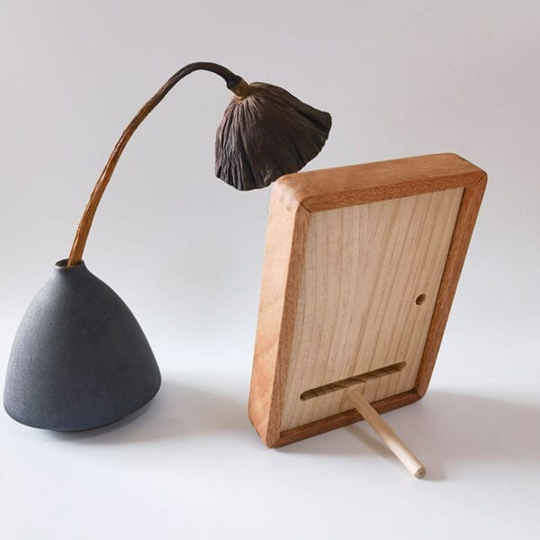 Holzbilderrahmen neben getrockneter Lotusblume in Vase. Hochwertiger Massivholz Fotorahmen.