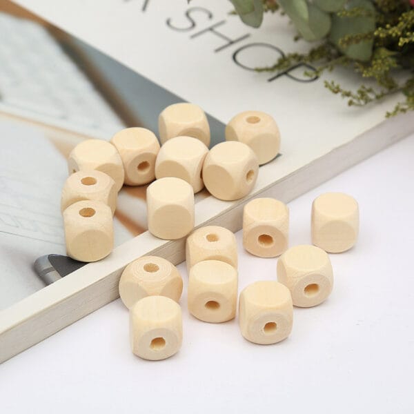 Naturfarbene, eckige Holzperlen mit großem Loch auf einem Buch. Polygonale Perlen.