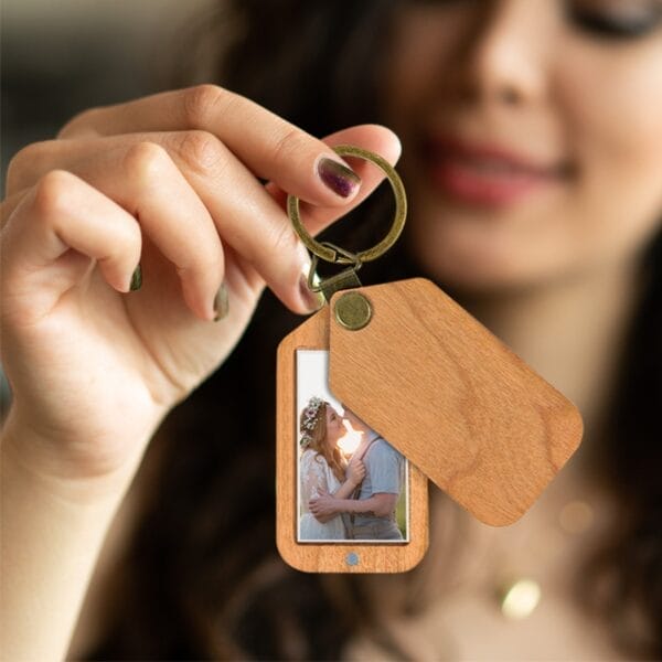 Frau hält personalisierten Holz-Fotoanhänger mit Paar. Schlüsselanhänger mit Foto Holz.
