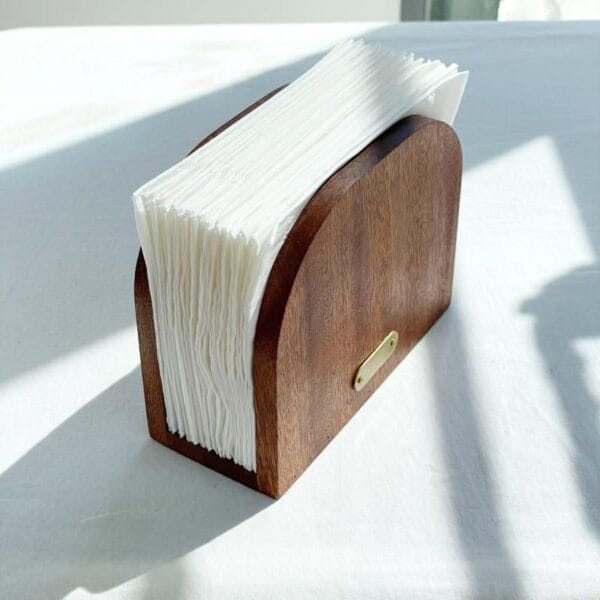 Serviettenhalter Holz mit weißen Servietten auf weißem Tisch. Stilvoller Tischhalter für Gastronomie.