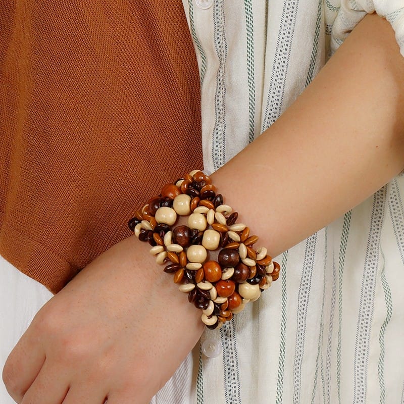 Handgelenk mit mehrreihigem Boho-Armband aus Holzperlen in Braun- und Beigetönen.