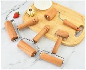 Kleine Buchenholz-Nudelhölzer und Gebäckroller auf einem Holzbrett, ideal für Bäckerei.