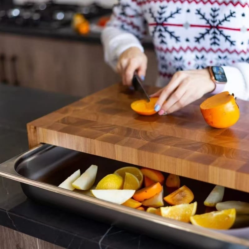 Frau schneidet Persimone auf Holz Schneidebrett mit Schublade für Abfall.