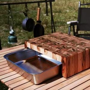 Holz Schneidebrett mit Schublade und Auffangschale auf einem Campingtisch.