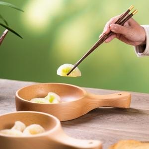 Holzschale mit Griff, gefüllt mit Speisen, Chopsticks halten ein Stück. Akazien- und Buchenholz.