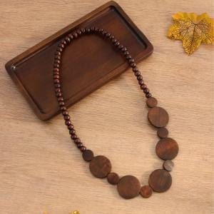 Wooden bead necklace with large circular pendants on a wooden tray. Boho jewelry.