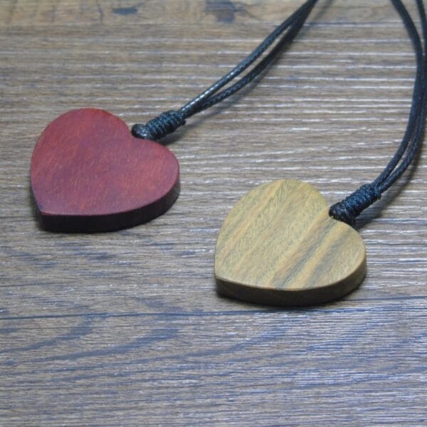 Zwei hölzerne Herzanhänger an schwarzen Kordeln, personalisierbarer Holzschmuck.