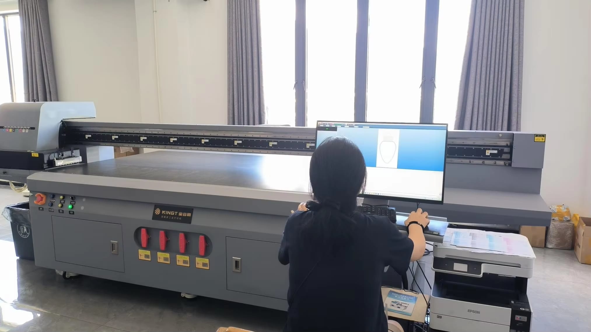 Technician operating a large format UV printer for industrial printing.