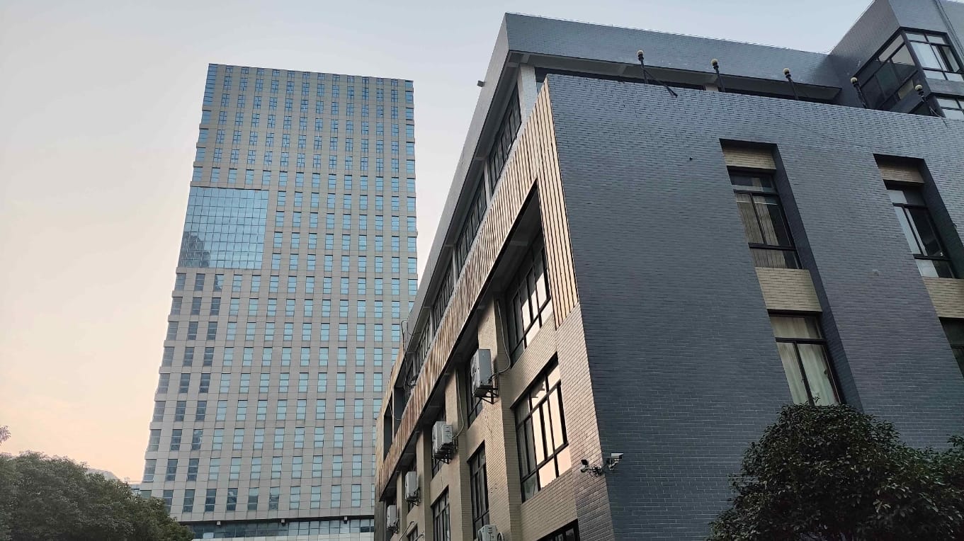 Modernes Bürogebäude mit Glasfassade und grauer Backsteinstruktur.