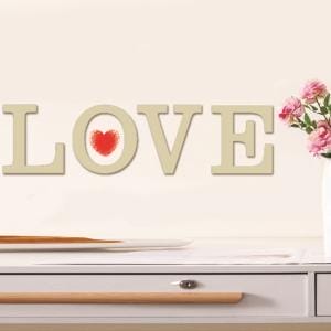 Große Holzbuchstaben "LOVE" mit rotem Herz an der Wand.