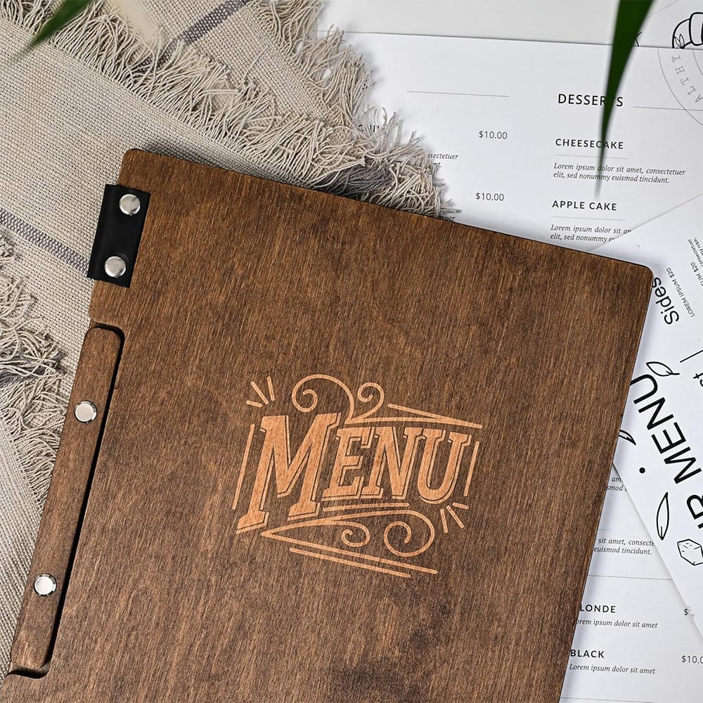 Holzmenü mit Aufschrift "MENU", Desserts- und Seitenkarte im Hintergrund.