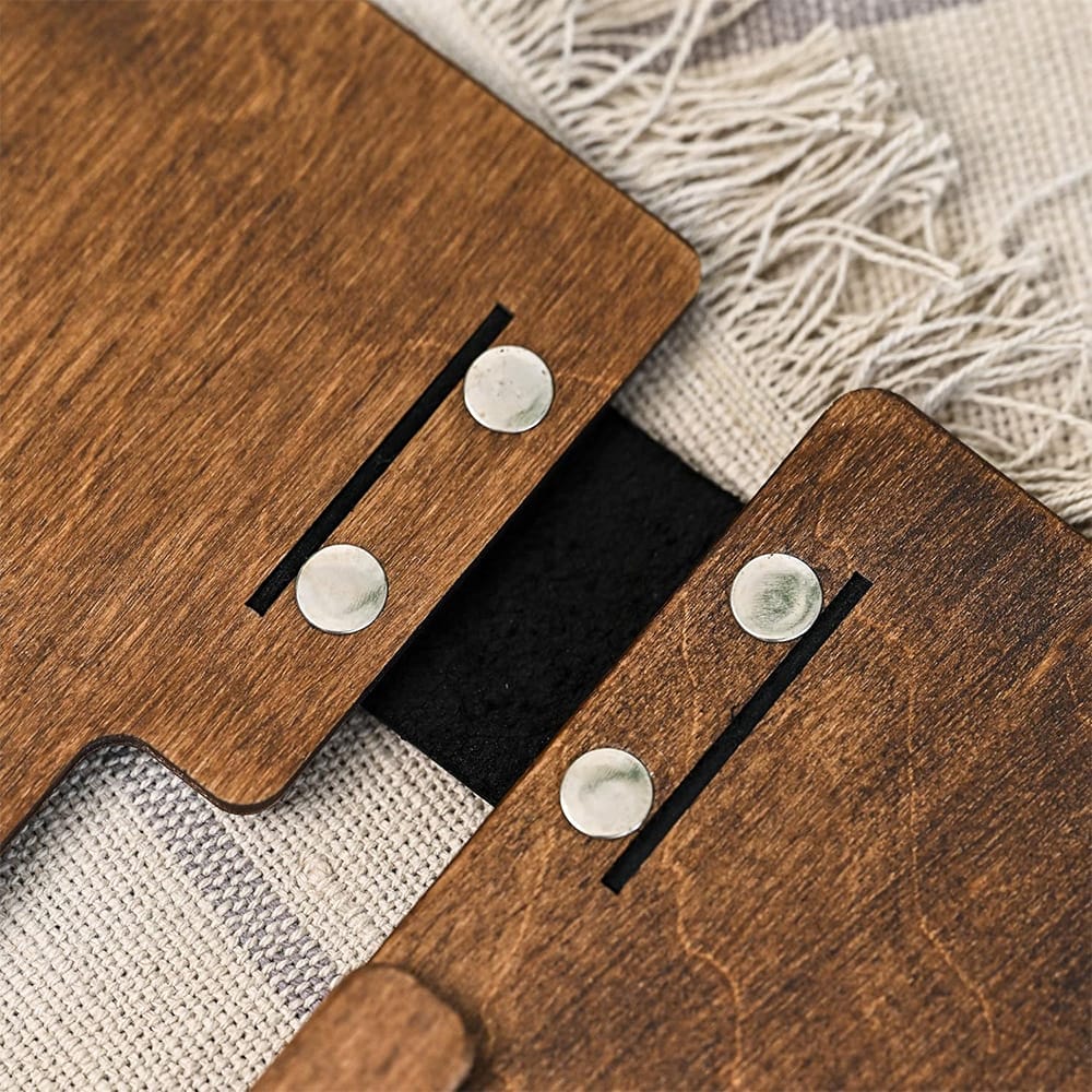 Nahaufnahme von zwei Holzstücken mit Metallknöpfen und einem schwarzen Band verbunden.