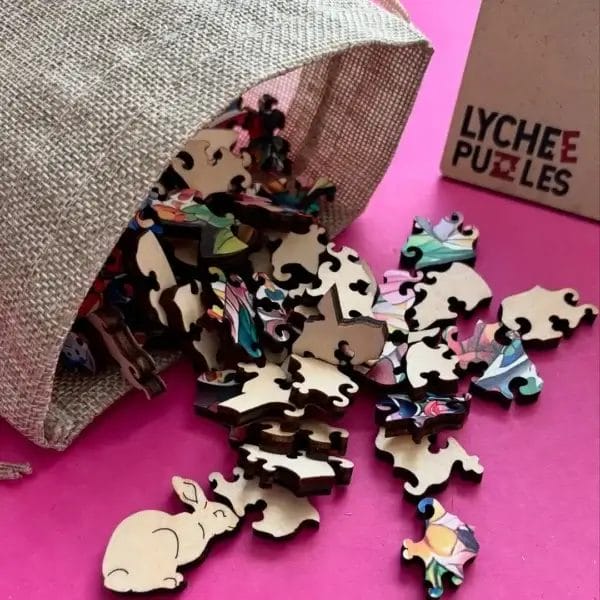 Holzpuzzle-Teile, darunter ein Hase, aus einem Beutel verschüttet, mit "Lychee Puzzles" Box. Hunde Puzzle aus Holz.
