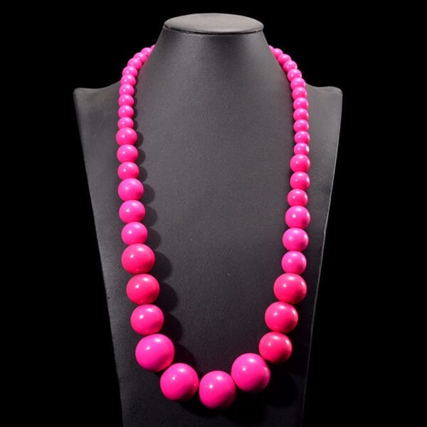Pinke Holzkette mit großen Perlen auf Schmuckständer. Boho-Kette aus Holzperlen.