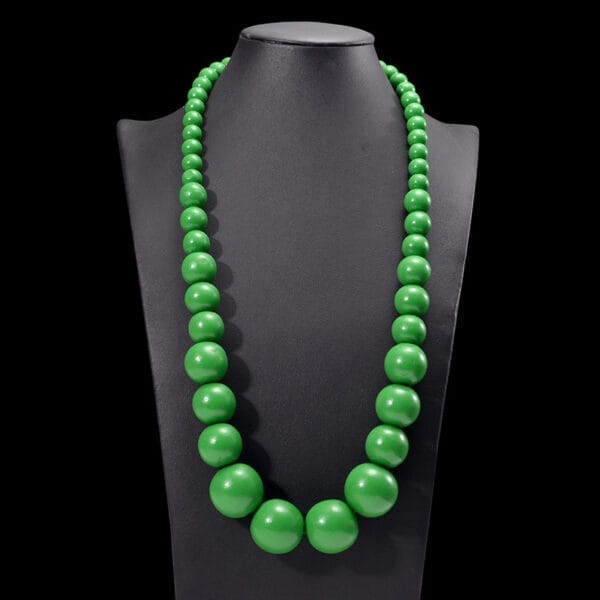 Grüne Boho-Kette aus Holzperlen auf Schmuckständer. Natürlicher Schmuck.