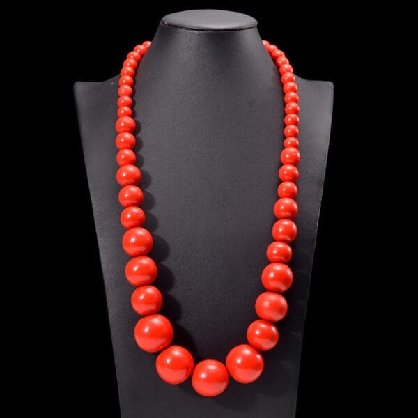 Rote Holzkette mit großen Perlen auf einer Schmuckbüste. Boho-Kette aus Holzperlen.