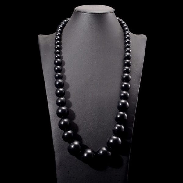 Schwarze Boho-Kette aus Holzperlen auf Schmuckständer. Natürlicher Schmuck.