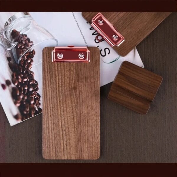 Klemmbrett Holz mit roségoldenen Klemmen und Kaffeebohnen auf einem Magazin.