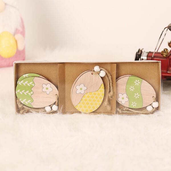 Osterdekoration: Drei hölzerne Ostereier mit Frühlingsmotiven in einer Geschenkbox. Küken Deko Ostern.