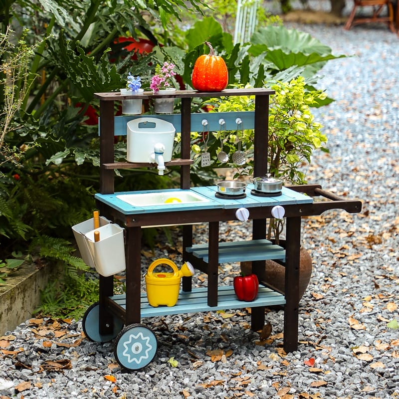 Spielküche im Garten mit Kürbis, Gießkanne und Töpfen. Outdoor-Matschküche für Kinder.
