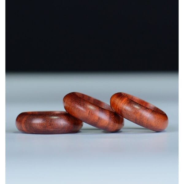 Drei hölzerne Armreifen auf einer weißen Oberfläche. Handgefertigter Schmuck.