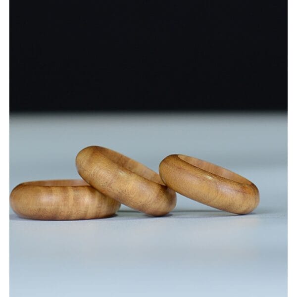 Drei hölzerne Armreifen auf einem Tisch, natürliche Holzfarbe.