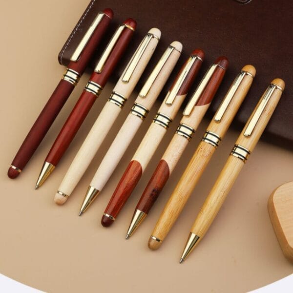 Personalisierte Holzkugelschreiber mit goldenen Akzenten, aufgereiht.