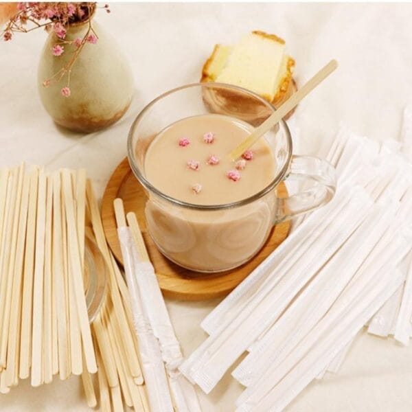 Holz Rührstäbchen neben Kaffee, Kuchen und Blumen. Bambus Kaffee- und Teerührer im Großhandel.