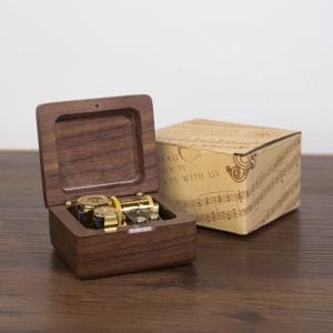 Hölzerne Spieluhr mit offener Box und Notenblatt-Verpackung.