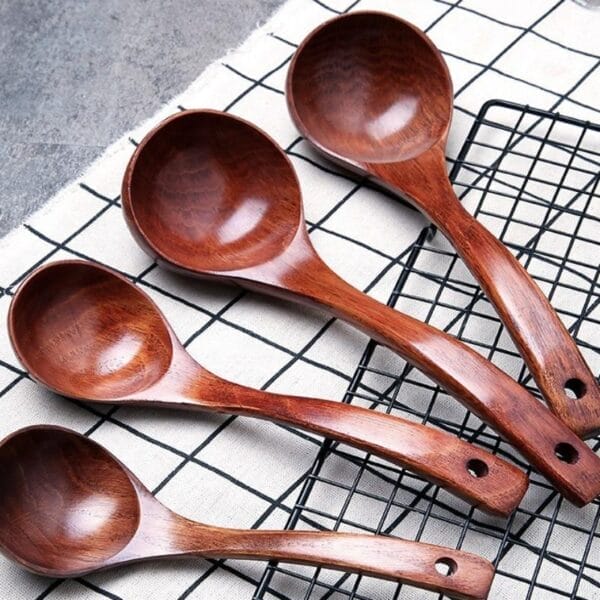 Mehrere Suppenlöffel aus Holz auf einem Küchentuch mit Karomuster.