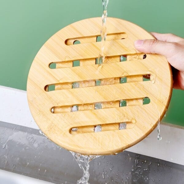 Hölzerner Topfuntersetzer aus Bambus unter fließendem Wasser. Hitzebeständig und rutschfest.
