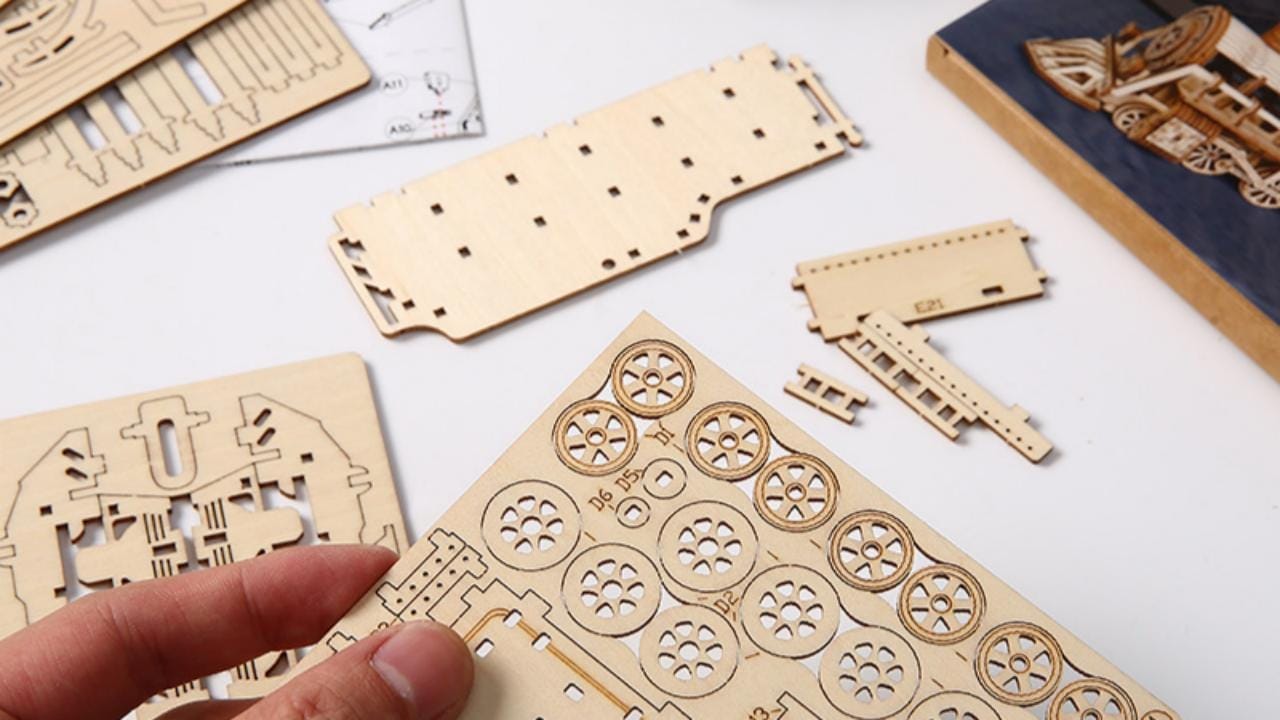 Holzbausatz für 3D-Puzzle, Räder im Vordergrund. Anleitung zum 3D-Puzzle zusammenbauen.